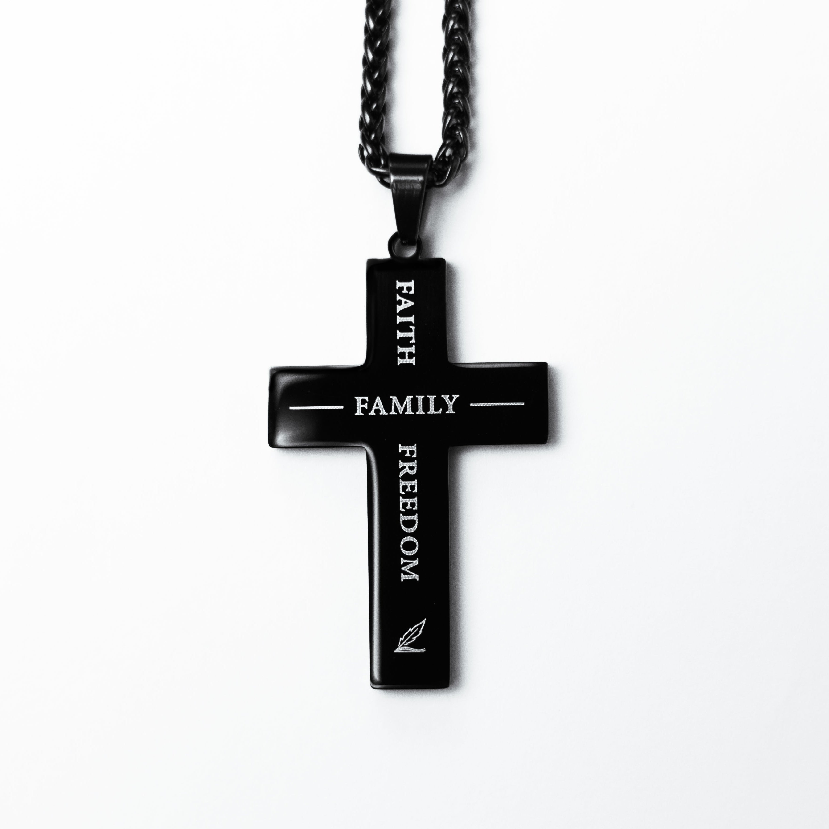 Black cross pendant necklace with engraved text on a white background