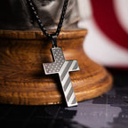 Silver cross pendant on a wooden stand with an American flag in the background